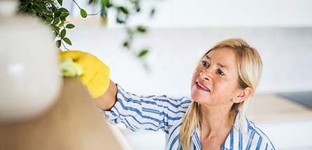 A woman wiping down a shelf.