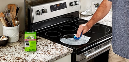 A person cleaning a glass stovetop with affresh.