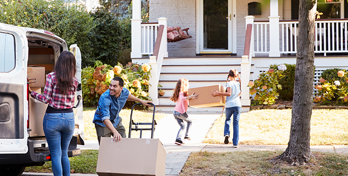 A family carries moving boxes into their new home.