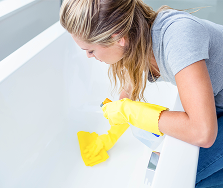 A woman wipes down a bathtub.