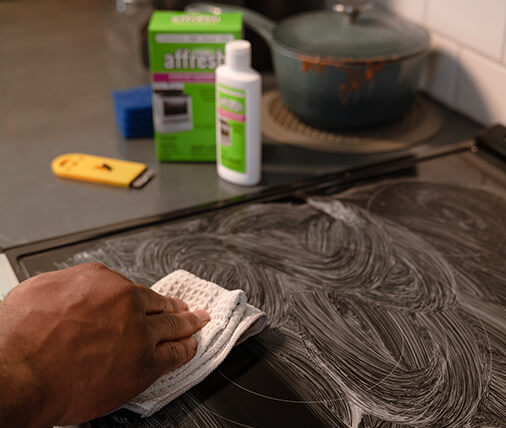 A person cleaning a glass stovetop with affresh.