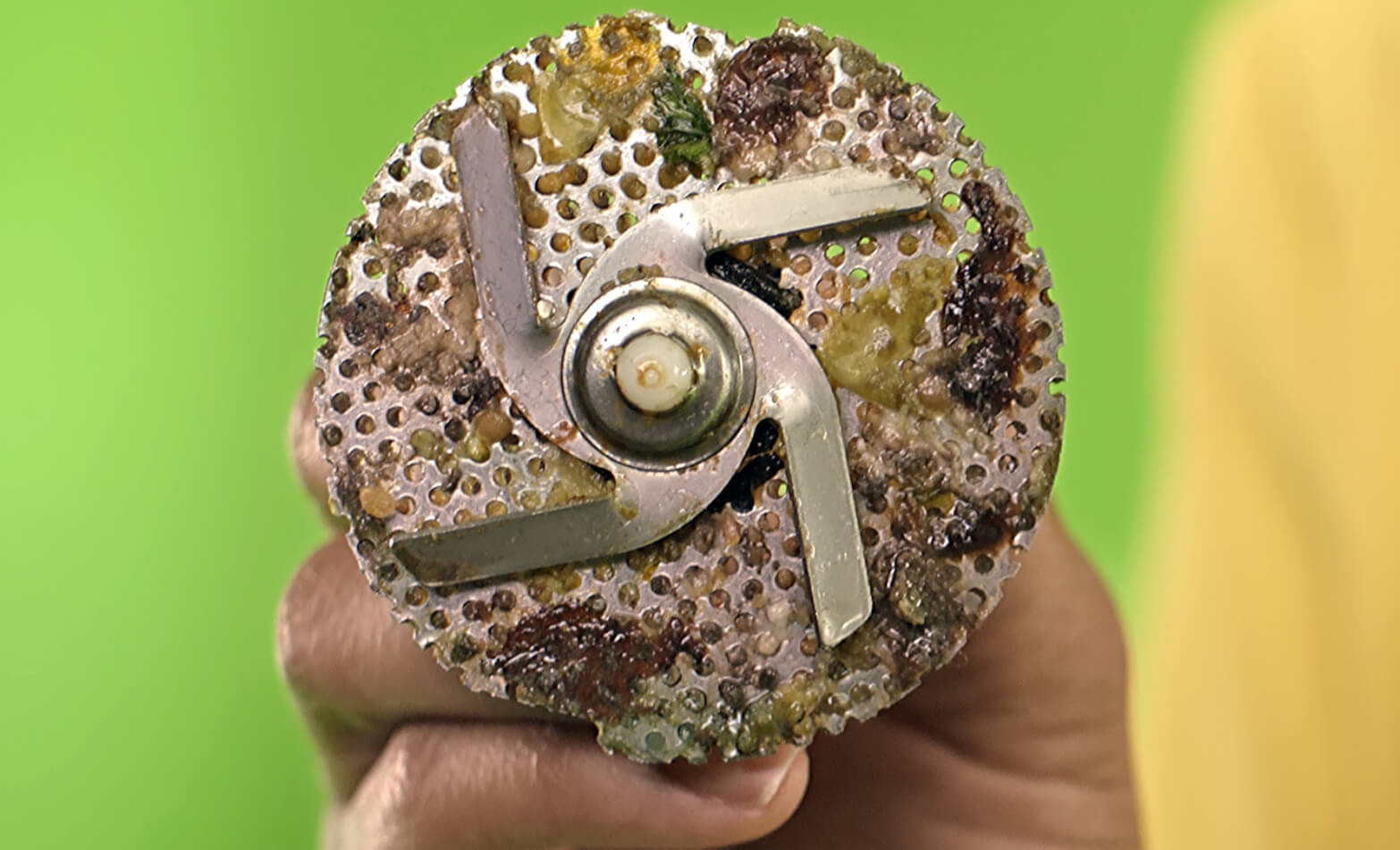 A person examines a dishwasher filter to see if it has food particle buildup.