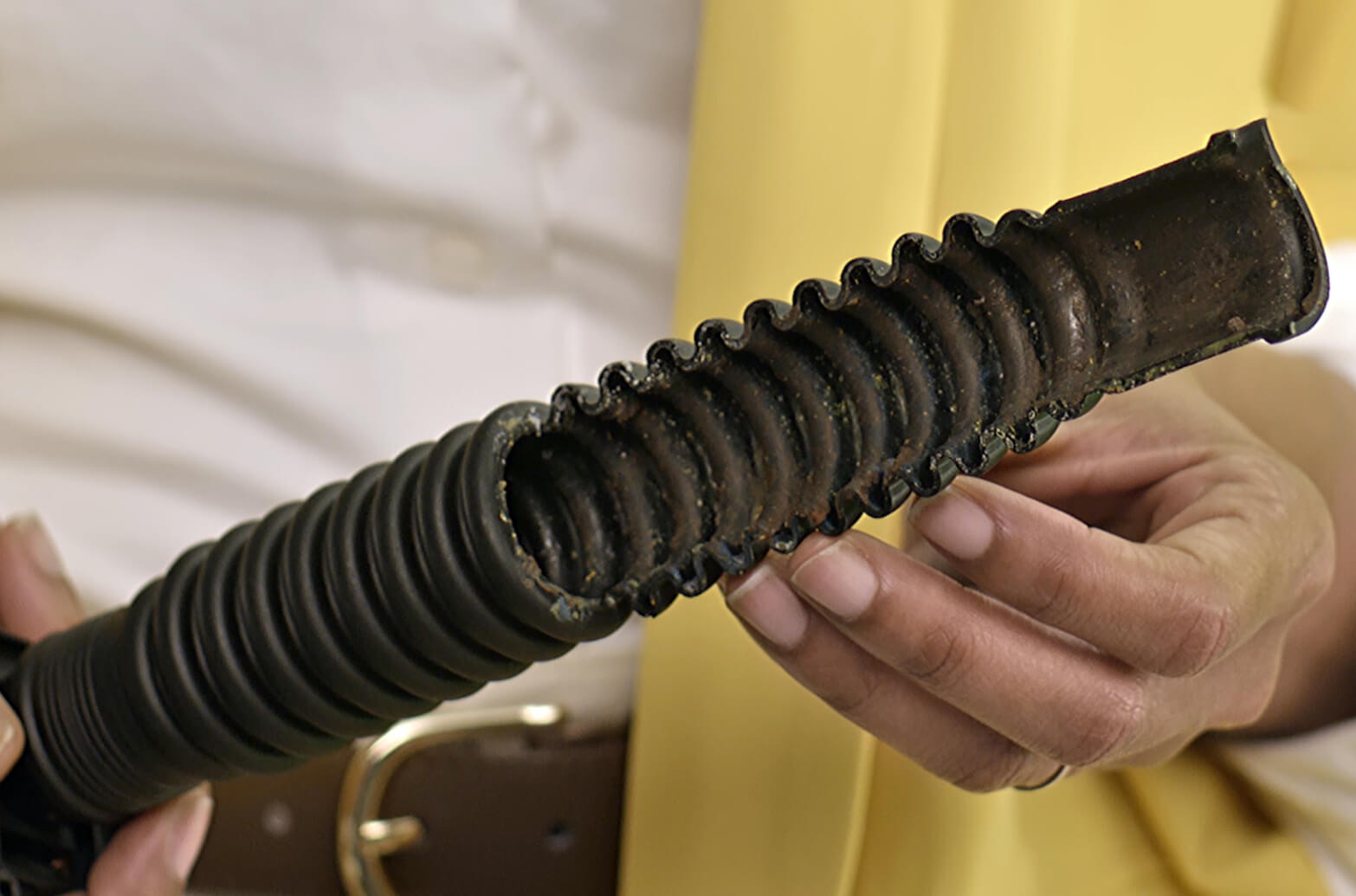 A person examines a dishwasher drain hose to see if it is damaged or clogged.
