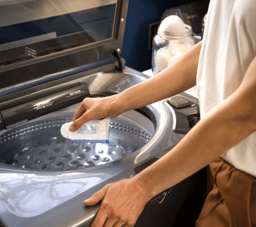 A person wiping a washing machine with a rag to clean